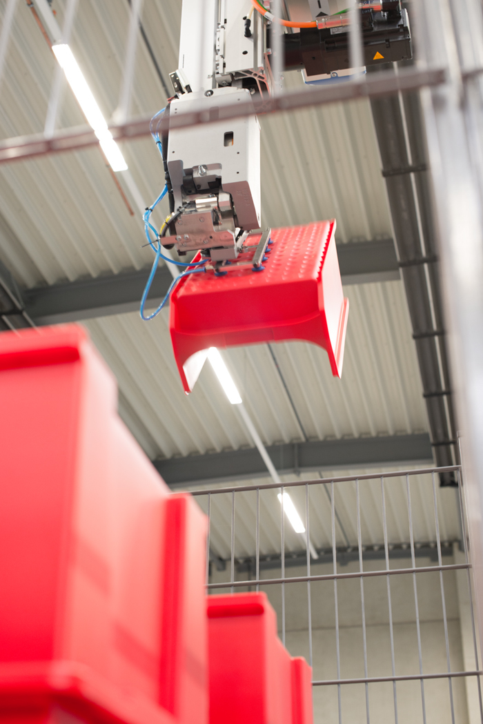 Sichtlagerbox wird nach der Fertigung von einem Roboter aufgenommen.